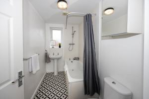 Beautiful 4 Bed House in Manchester Free Parking في مانشستر: حمام أبيض مع حوض ومغسلة