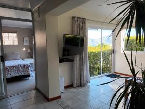 a bedroom with a bed and a balcony with a television at Sea Cottage in Hout Bay