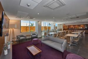 a restaurant with tables and chairs and a couch at City Express by Marriott Rosarito in Rosarito