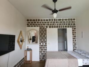 a bedroom with a brick wall and a bed at Guest House Flor de Laranjeira in São Pedro da Aldeia