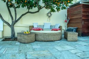 a patio with a couch and two chairs and an orange tree at Maya's home in Dhaskalión