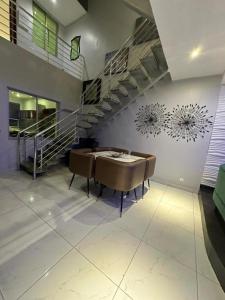 a dining room with a table and chairs and a staircase at Blue Bell Suites in Lekki
