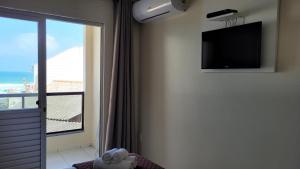een kamer met een tv aan de muur en een raam bij Pousada Sol e Mar Ingleses in Florianópolis