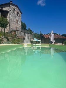 uma piscina de água com dois guarda-sóis e um edifício em Borgo Vetrianello em Lucca