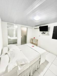 a white bedroom with a bed and a tv at Terras Verdes Residence in Fernando de Noronha