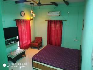1 dormitorio con cortinas rojas, 1 cama y 1 silla en Krushna Kunj Holiday Home, en Alibaug