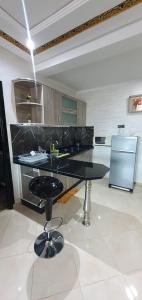 uma cozinha com um balcão preto e um banco em Suite Home Prestige em Kenitra