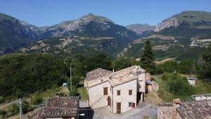 una casa vieja en una colina con montañas en el fondo en Un sogno nel bosco, en Montefortino