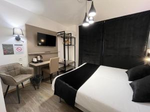 Dormitorio con cama, escritorio y TV en Cit'Hotel Le Cheval Blanc Cognac Centre, en Cognac