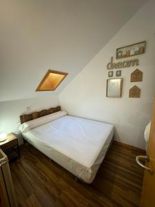 a bedroom with a white bed with a skylight at Acogedor Ático en el Corazón de Formigal in Formigal