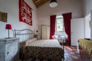 a bedroom with a bed and a window with red curtains at Agriturismo La Contessa in Finale Ligure