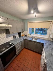 una pequeña cocina con fregadero y ventana en Lovely Furnished 1 Bedroom Flat in historic St Albans. Sleeps 4, en Saint Albans