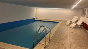 a swimming pool with white chairs in a room at FeWo Talblick 22 in Bad Lauterberg