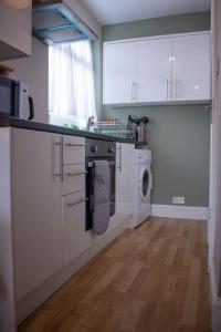 a kitchen with white cabinets and a washing machine at Cosy apartment 7 mins walk from Wembley stadium in London