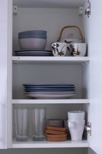 a white cabinet with plates and bowls and dishes at Cosy apartment 7 mins walk from Wembley stadium in London