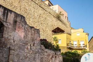 a building next to a stone wall with a building at Manno 81 - Charming historic apartment in Cagliari