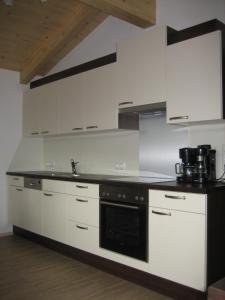 uma cozinha com armários brancos e um forno preto em Haus Barbara Breuer em Neukirchen am Grossvenediger