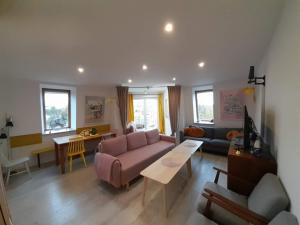 a living room with a pink couch and a table at Apartament Puck Przestronny i Nowoczesny in Puck
