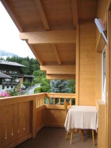 einen Holzbalkon mit einem Tisch und einem Fenster in der Unterkunft Haus Barbara Breuer in Neukirchen am Großvenediger