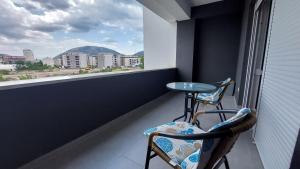 einen Balkon mit 2 Stühlen, einem Tisch und einem Fenster in der Unterkunft Studio Apartment Smile Mostar in Mostar
