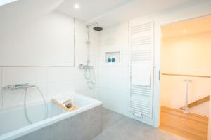 a white bathroom with a tub and a shower at Sleeping Home - Red House in Bielefeld