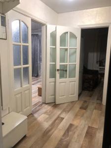 un soggiorno con porte bianche e pavimenti in legno di Квартира Пентагон a Korostenʼ