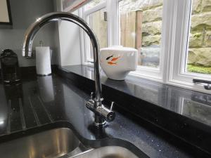 - un évier de cuisine avec un distributeur de savon à base de poisson à côté d'une fenêtre dans l'établissement Luxury Home With Stunning River Views, à Knaresborough