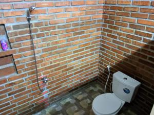 een bakstenen badkamer met een toilet in een bakstenen muur bij Omah Mbah Manten in Tuntang