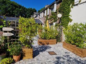 un jardin avec des plantes en pot devant un bâtiment dans l'établissement La Fontaine de Resnel, à Fréhel