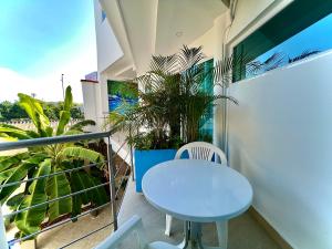 une table et des chaises blanches sur un balcon avec une plante dans l'établissement Charme 64 Hotel Boutique Aeropuerto, à Carthagène des Indes