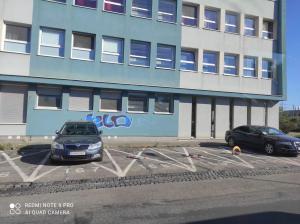 dos autos estacionados en un estacionamiento frente a un edificio en 1 - izbový apartmán s kúpeľňou, en Bratislava