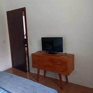 TV en un tocador de madera en un dormitorio en Quartos para Hospedagem da Casa Amarela, en Campos do Jordão