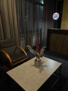 una mesa con un jarrón de flores y una silla en LEX Trend Hotel, en Irpín