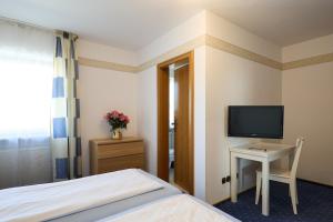 a bedroom with a bed and a desk with a television at Hotel Garni Demmel in Bruckmühl