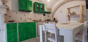 a kitchen with green cabinets and a table with chairs at MI PUGLIA Casa vacanze in Putignano