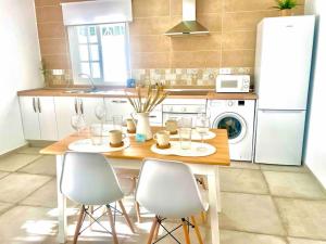 eine Küche mit einem Holztisch mit Stühlen und einem Kühlschrank in der Unterkunft Brisa Home in Chiclana de la Frontera