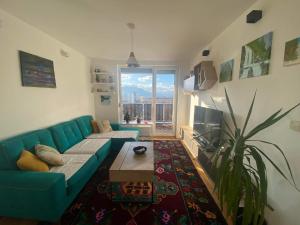 a living room with a blue couch and a large window at Sunset Panorama in Sarajevo