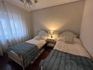 Duas camas num pequeno quarto com uma janela em Apartamento La Luz de Reinosa 3 em Reinosa