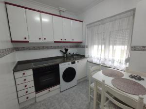 Apartamento La Luz de Reinosa 3 في رينوسا: مطبخ مع دواليب بيضاء وطاولة وصالة طعام