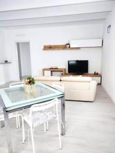 Inzago的住宿－Casa Spaziosa in centro Paese，客厅配有玻璃桌和白色椅子