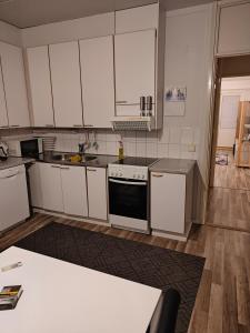 uma cozinha com armários brancos e um forno com placa de fogão em Js House em Pori