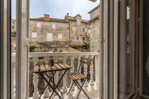 a balcony with a table and a view of a building at Riva Apartments Villa Thalia - Milna, Brač in Milna