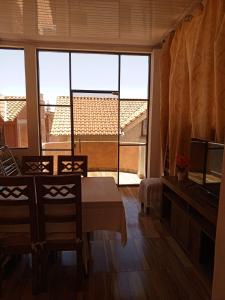 a dining room with a table and chairs and a large window at Departamento 1 casa Iglesias in Sucre