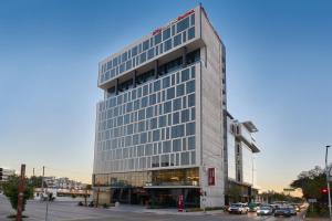 un edificio alto de cristal en una calle de la ciudad en City Express Suites by Marriott Tijuana Rio en Tijuana