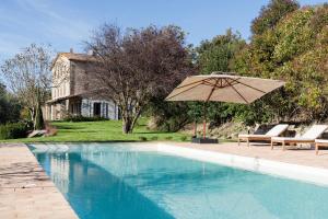 una piscina con ombrellone e sedie e una casa di CASALE ORTALI - Miani Group a Pesciano