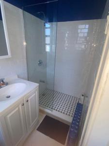 baño blanco con ducha y lavamanos en Peaceful House near Manhattan en Queens