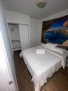 a bedroom with a white bed with a painting on the wall at Cozy Apartments Woodside near Manhattan in Queens