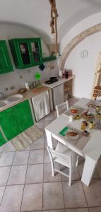 a kitchen with a white table and green cabinets at MI PUGLIA Casa vacanze in Putignano
