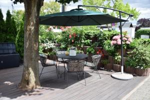 a table and chairs with an umbrella on a deck at Niebuhrs Hotel in Friedrichsdorf