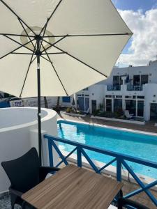 ein Tisch mit Sonnenschirm neben einem Swimmingpool in der Unterkunft 26 Puerto del Carmen Palm tree in Puerto del Carmen